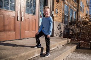 a first-grade boy standing on the school steps