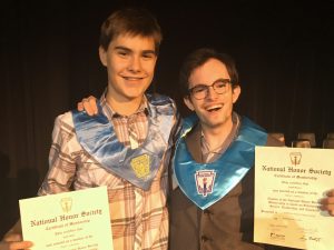 two male high school students hold their NHS certificates
