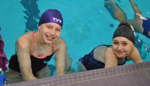 Two simmers in the pool smiling at the camera