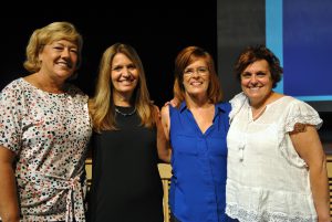A group of teachers smile after receiving their service pins for dedication to the district.