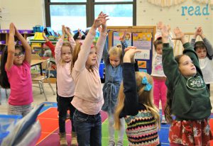 Students stretching their arms high in the classroom