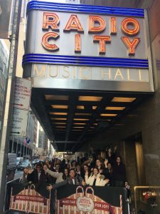 Groupof students waving outside of Radio City Music Hall